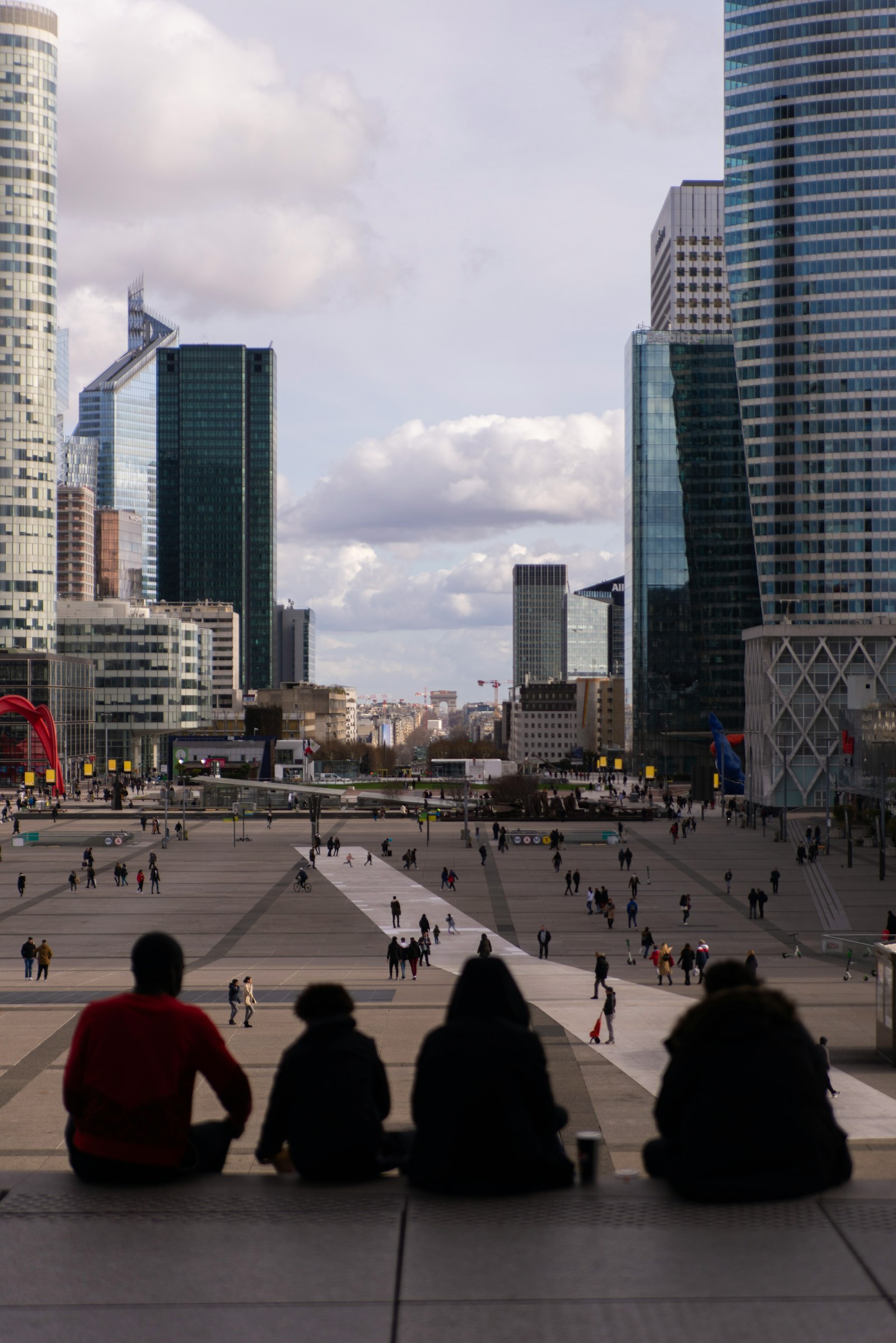 Des personnes regardent l’esplanade de La Défense, entre bureaux, ville et espace public.